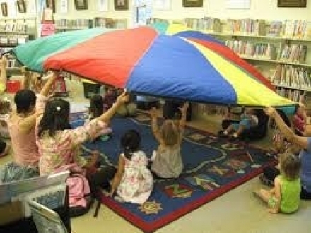 Students with colorful parachute in classroom
